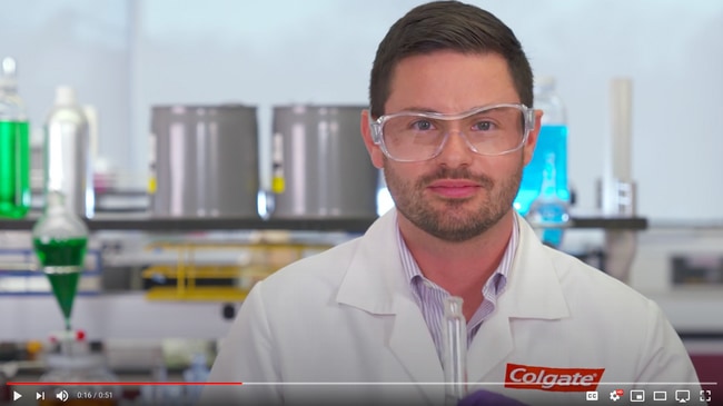 scientist wearing goggles standing in front of a lab setting with test tubes and beakers