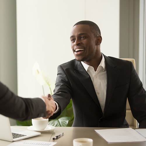 Two men in suits shaking hands in an office setting