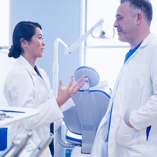 Two doctors speaking  as the female doctor has her hands out in frustration  in the treatment room