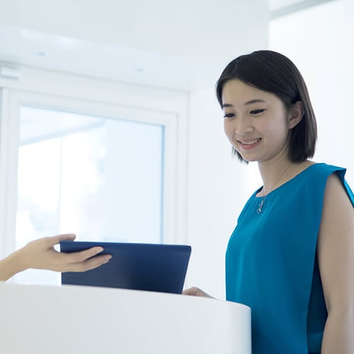Doctor extending her arm out as she holds a tablet to allow the patient to see what's on the screen