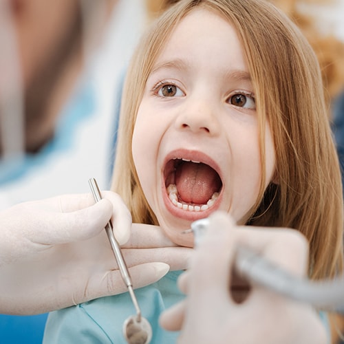 Dental professional inspecting a little firls mouth