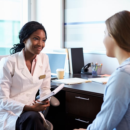 Patient and a doctor who is holding a chart smiling while sitting in an office