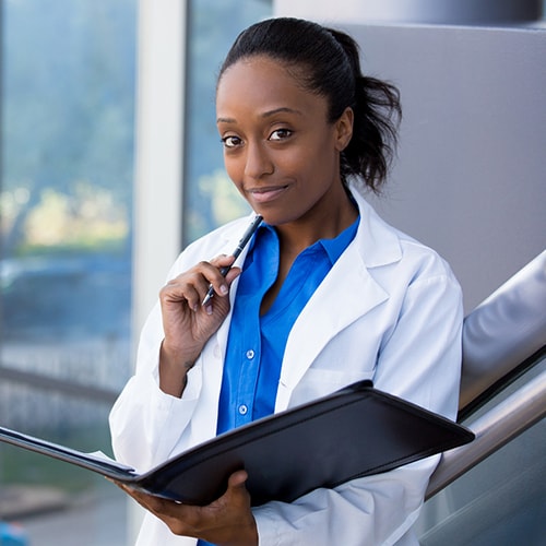 A young doctor holding an open folder and a pen to her chin