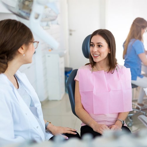 Patient and dentist talking while a nurse sits in the back on the computer